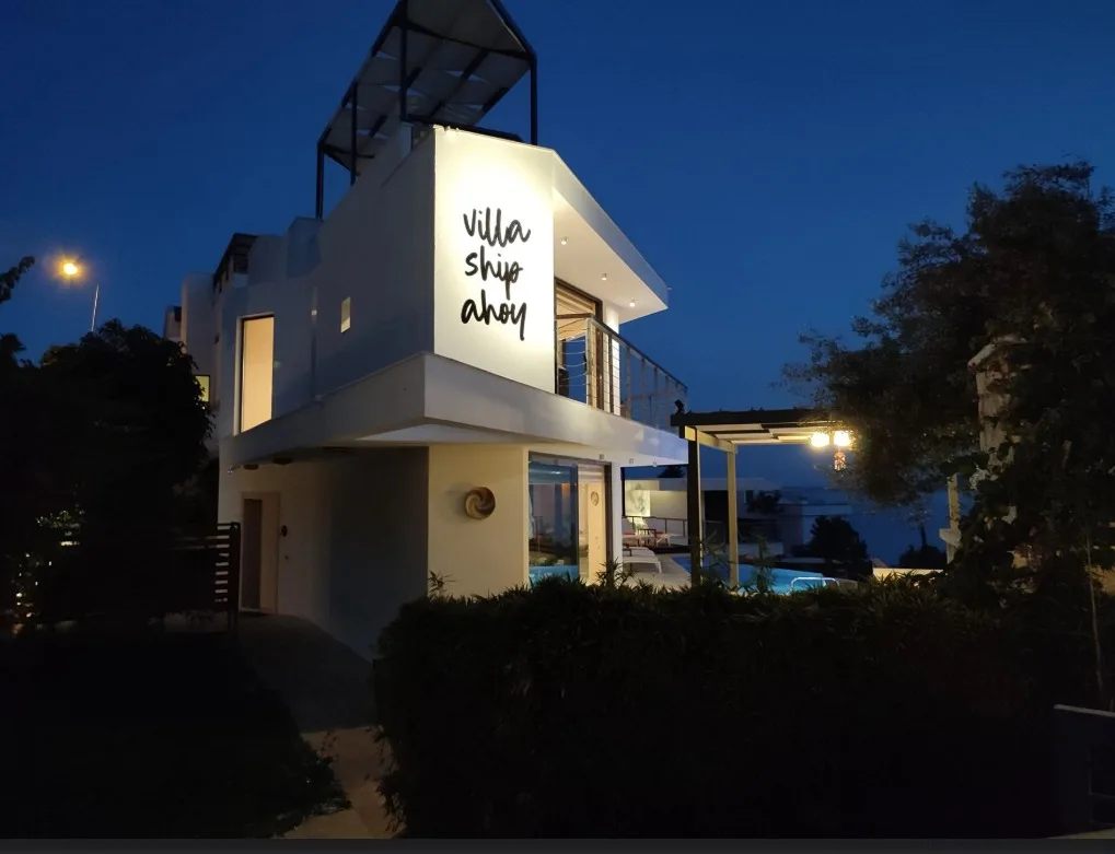 Villa Ship Ahoy'un beyaz duvarındaki el yazısı marka tabelası, alacakaranlıkta